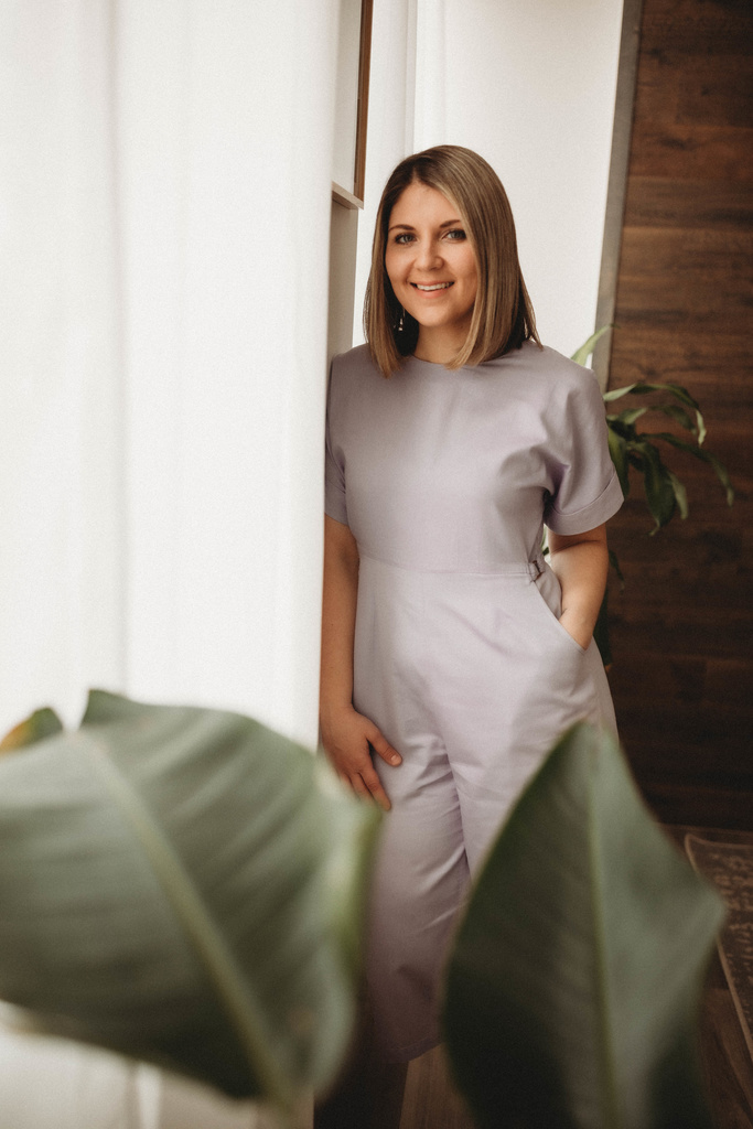 dr. anna garber naturopathic doctor standing next to white window curtains with plant in forefront
