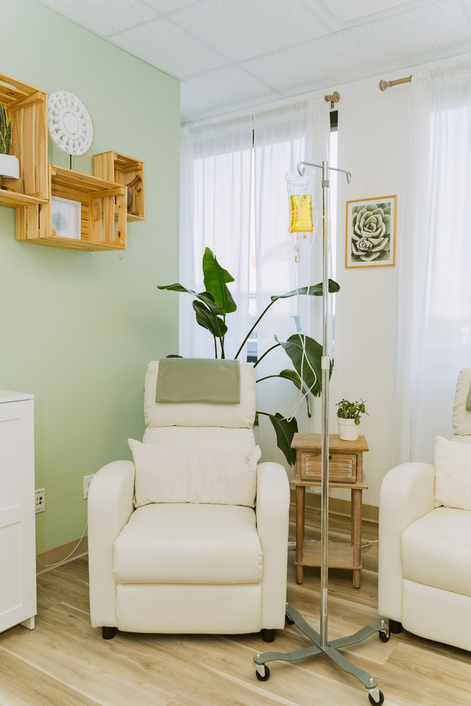 juniper naturopathic clinic fort mcmurray IV therapy office with lounge chair and IV bag hanging in treatment room against green wall and window in the background