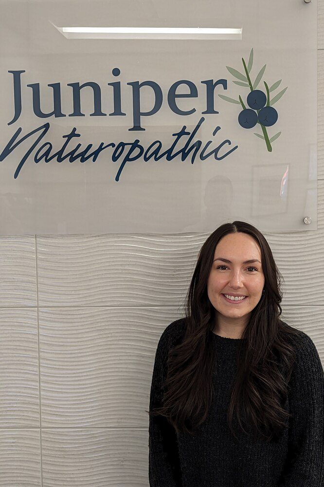 Molly Beringer standing infront of Juniper Naturopathic Sign at clinic