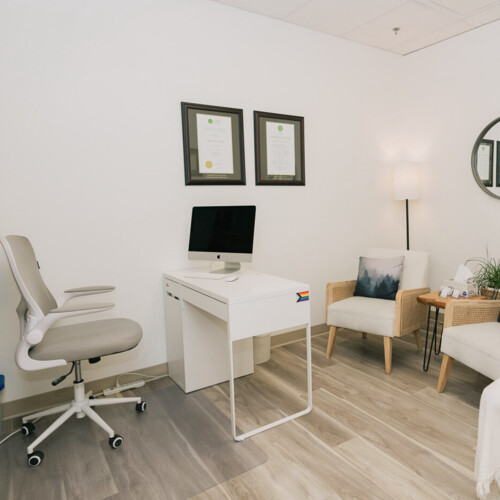 juniper naturopathic clinic fort mcmurray consultation room with treatment table-desk-chairs-side tables and naturopathic diploma lgbtq2s+ rainbow flag sticker cropped